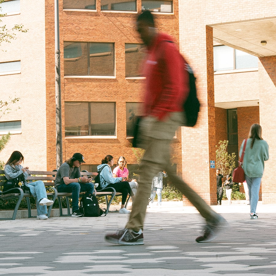 student in motion walking through the Quad