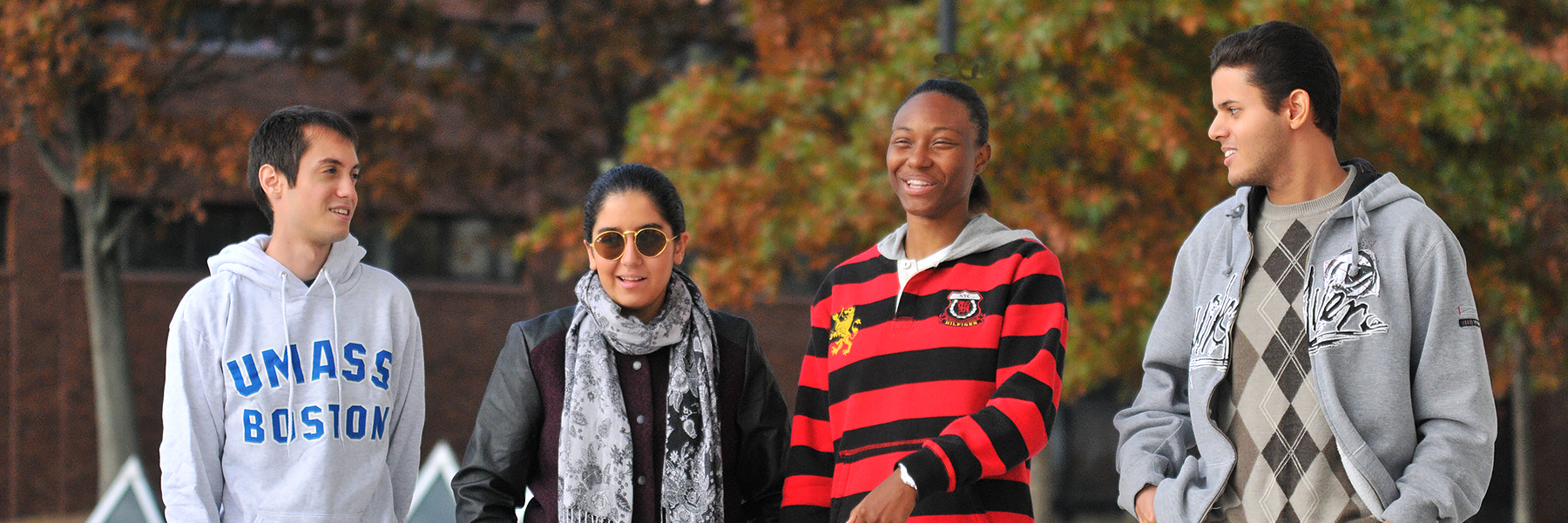 4 students walk on UMass Boston plaza.