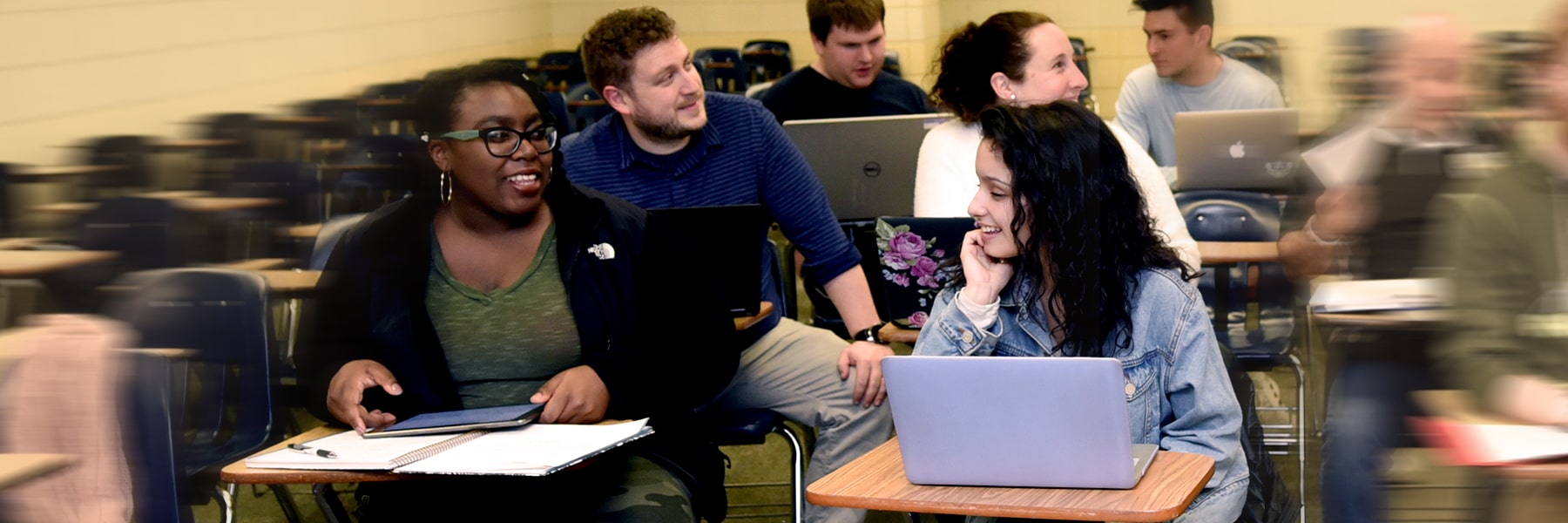 Students in a classroom talk to each other.