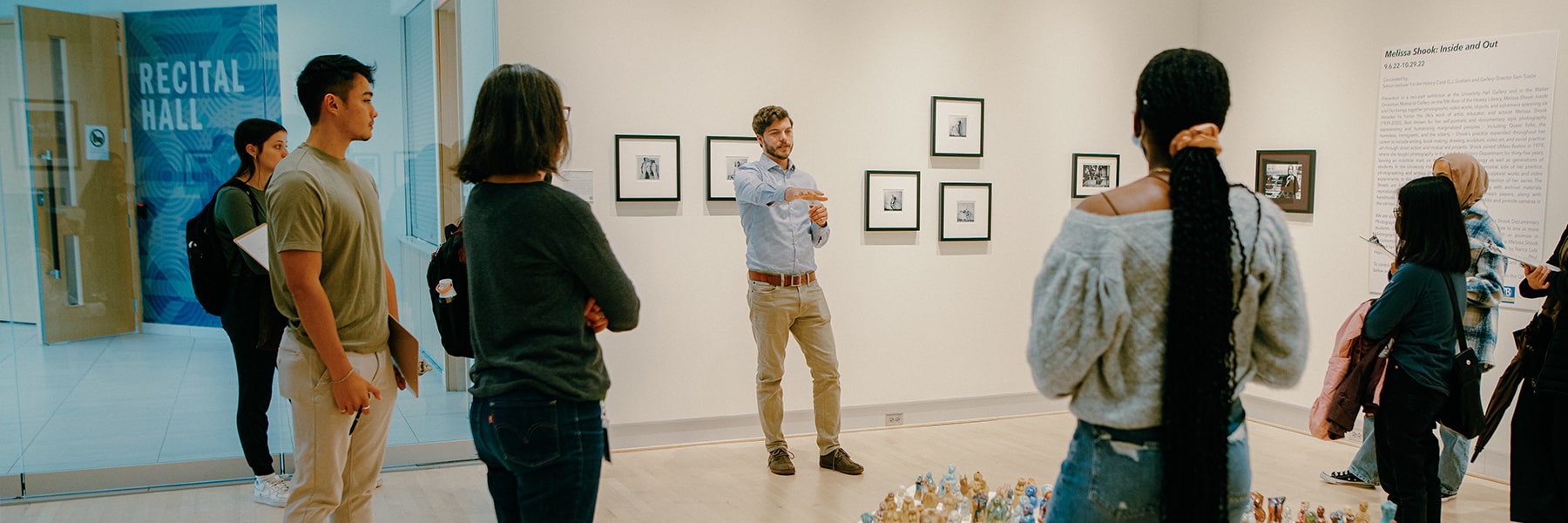 students listen to speaker in the campus art gallery.