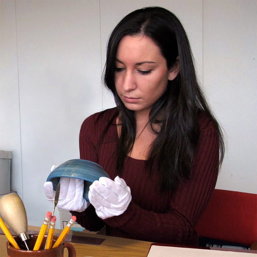 Student examining and working on pottery.