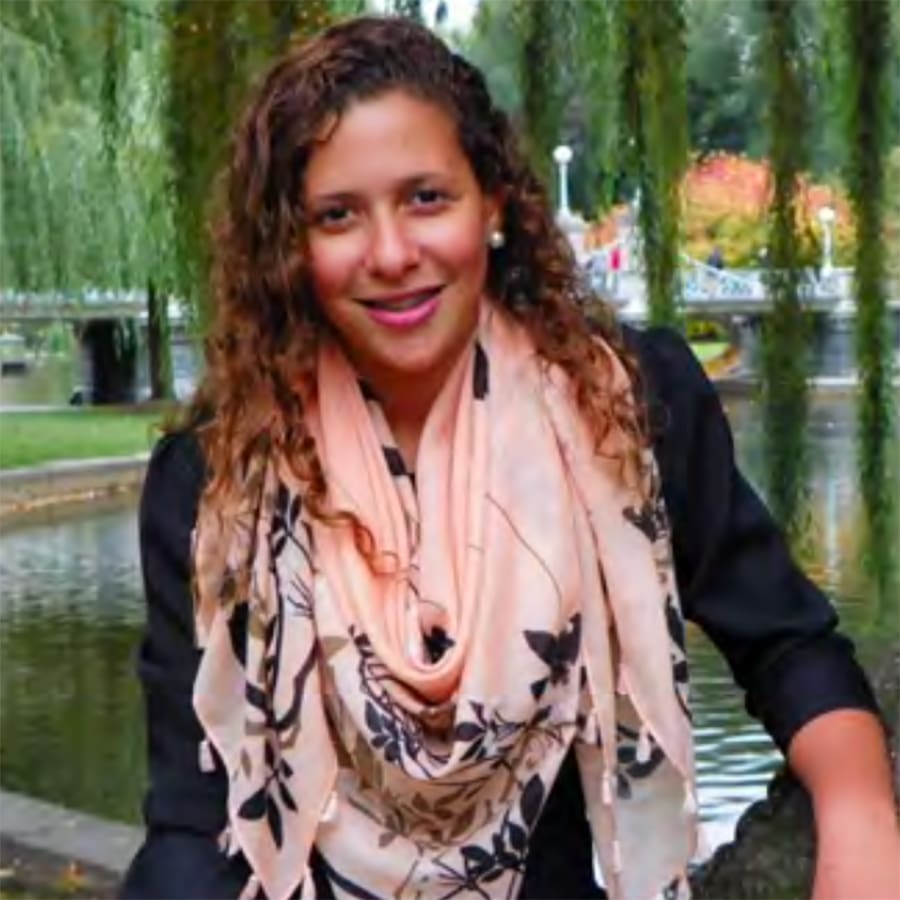 Student, Tayla, wearing bright pink scarf, sitting in front of pond.