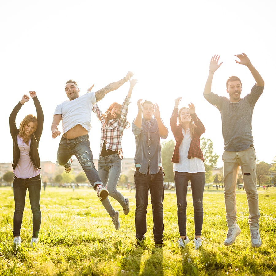 students jumping in celebratory mode sunlit streaming in from behind subjects