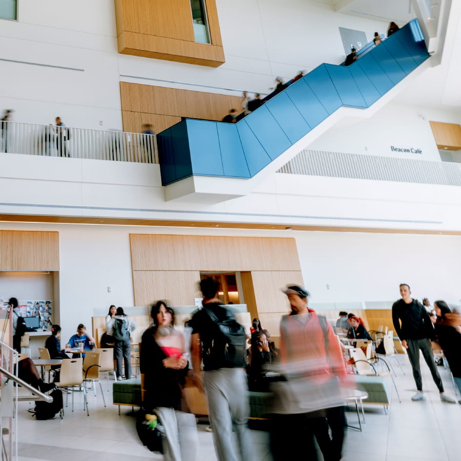 Crowd of students walking in University Hall atrium blurred view in motion.